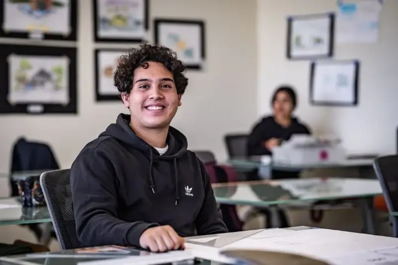 Hombre joven en aula universitaria sonriendo