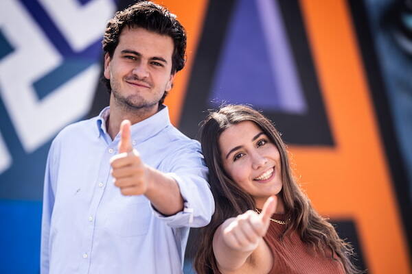 Estudiantes de la anahuac en el patio del campus con el pulgar arriba frente a un banner de la universidad