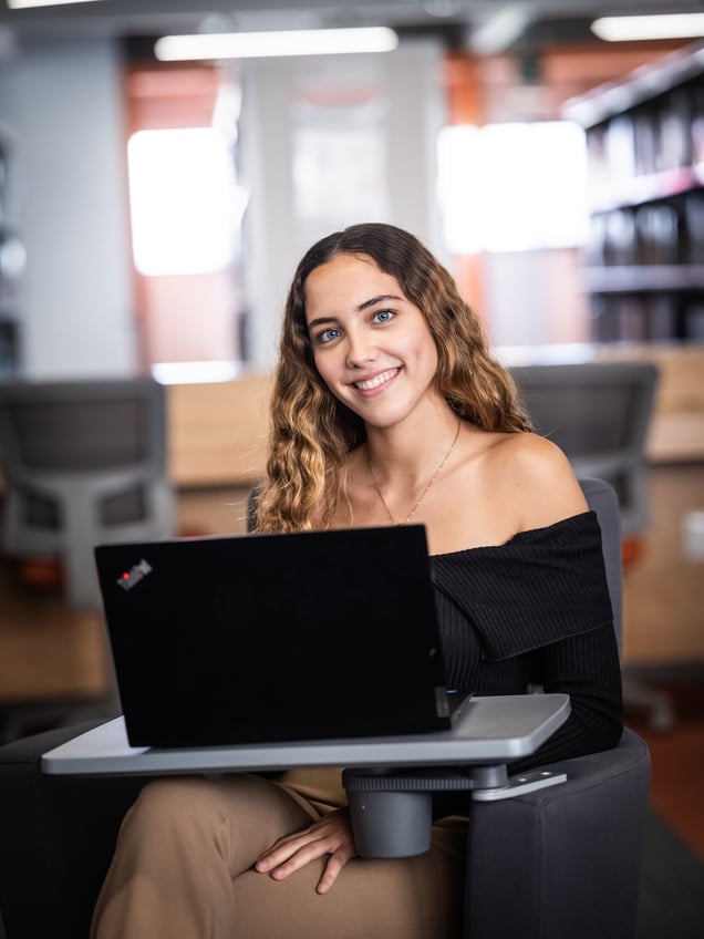 Mujer sonriendo al trabajar en su computadora dentro del salón de clases