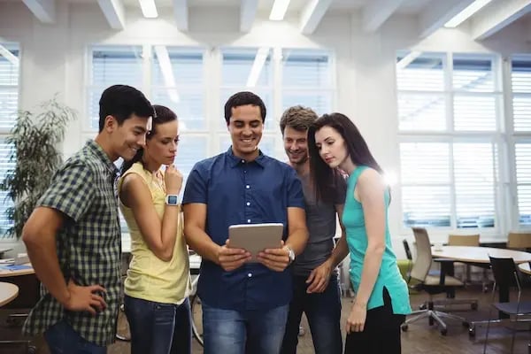 grupo de personas en oficina viendo una tablet