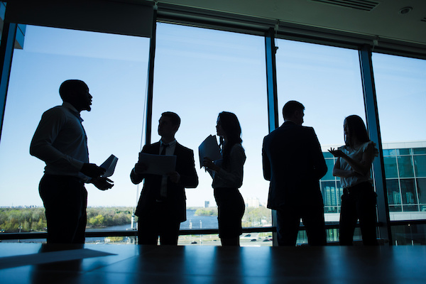 personas en oficina platicando enfrente de ventana