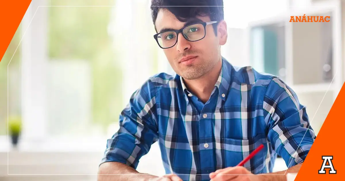 Estudiante de actuaría tomando notas en camisa a cuadros y lentes