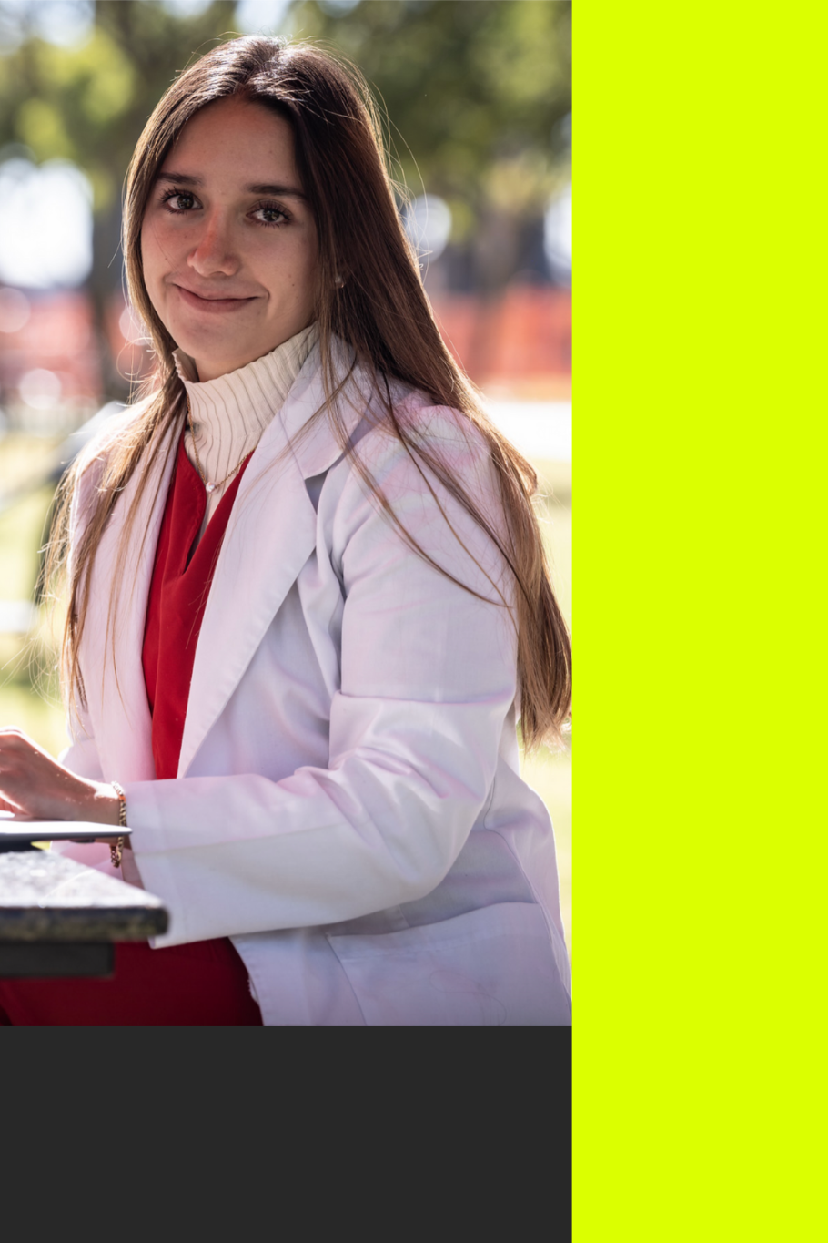 Joven estudiante sentada al aire libre dentro de las instalaciones de la universidad Anáhuac Puebla sonriendo.